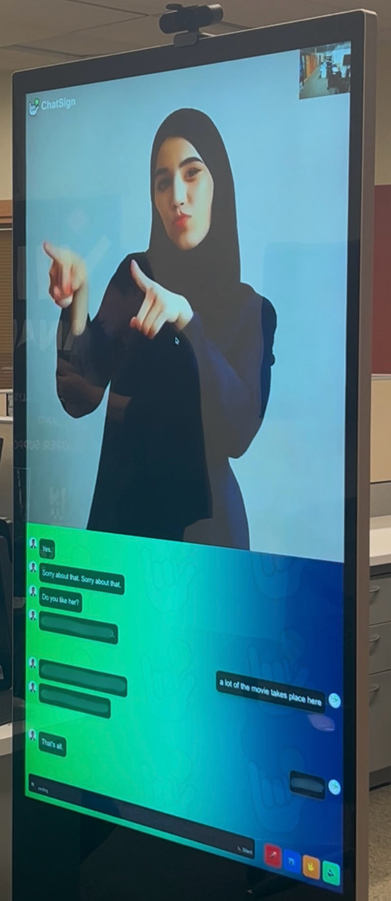 A tablet showing a sign language avatar on a desk in an office.